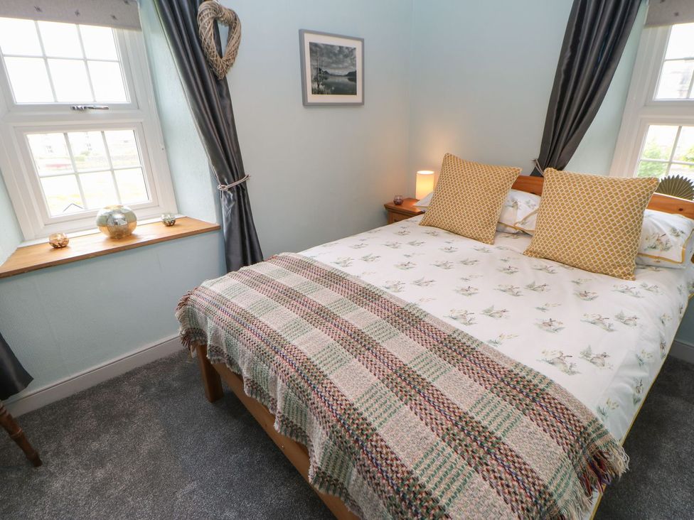 A bedroom with a bed and windows at Orchard Cottage in Appleby-in-Westmorland