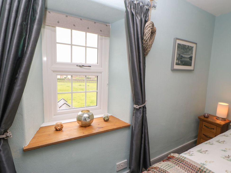 A bedroom with a window and decorative items on the sill at Orchard Cottage in Appleby-in-Westmorland