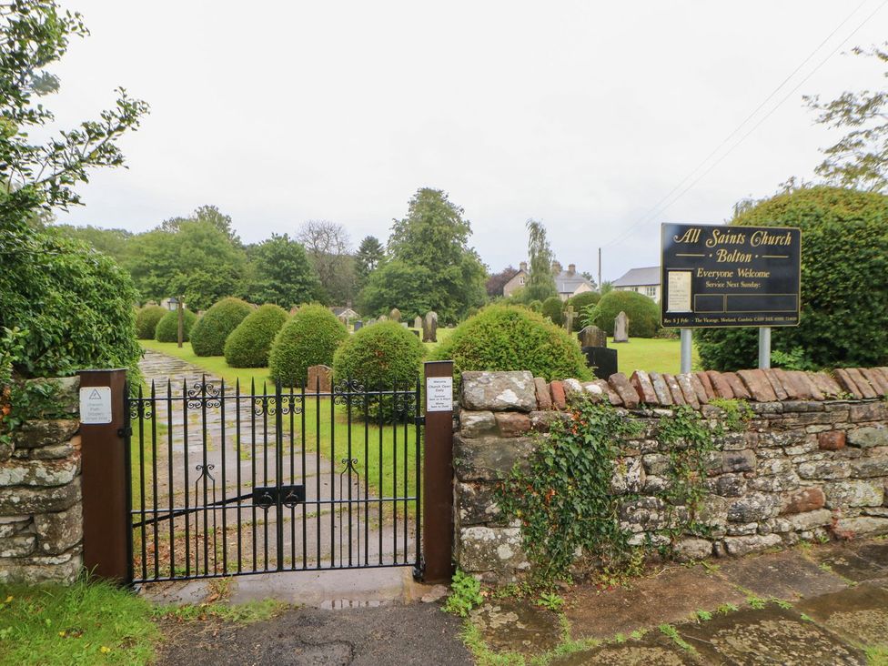 A gate leading to All Saints Church with a sign in Bolton