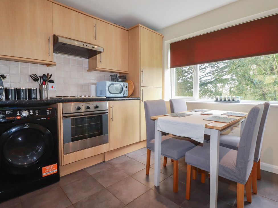 A kitchen with cabinets, stove, and dining table at Poolside, Atlantic Reach resort, near St Columb Major