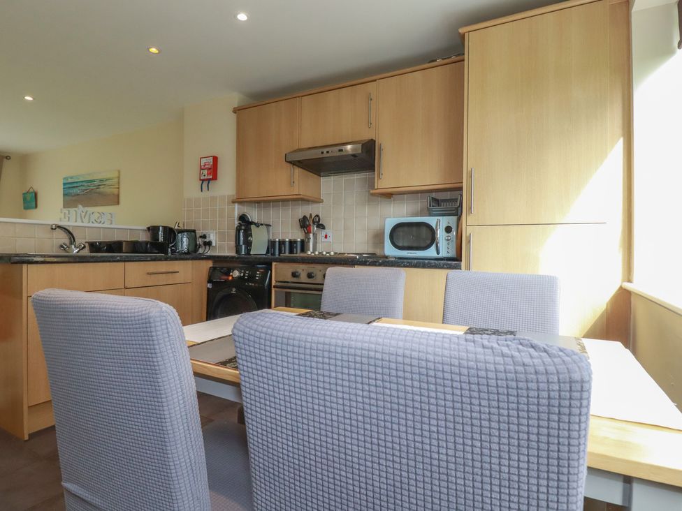 A kitchen with cabinets, sink, oven, and table at Poolside, Atlantic Reach resort, near St Columb Major