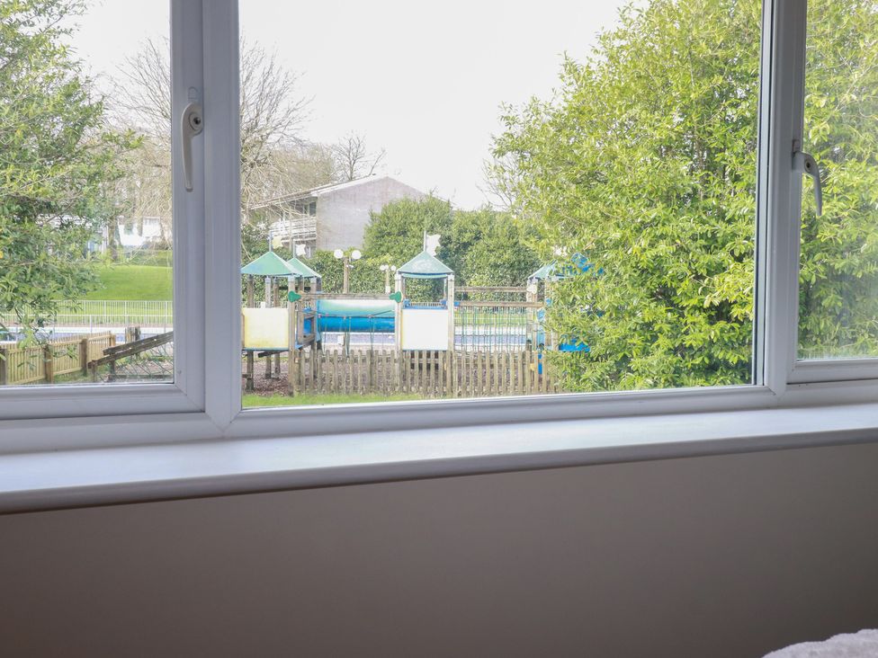 A view from a window showing a playground and trees at Poolside, Atlantic Reach resort, near St Columb Major