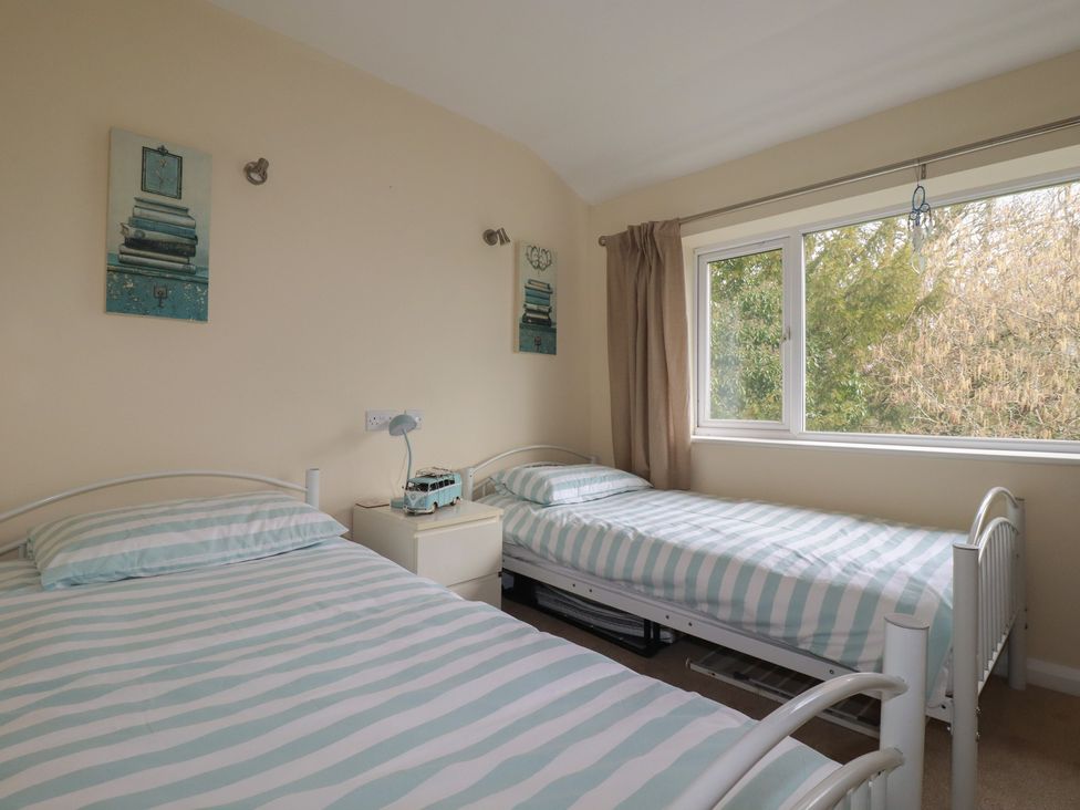 A bedroom with two single beds and a window at Poolside, Atlantic Reach resort, near St Columb Major