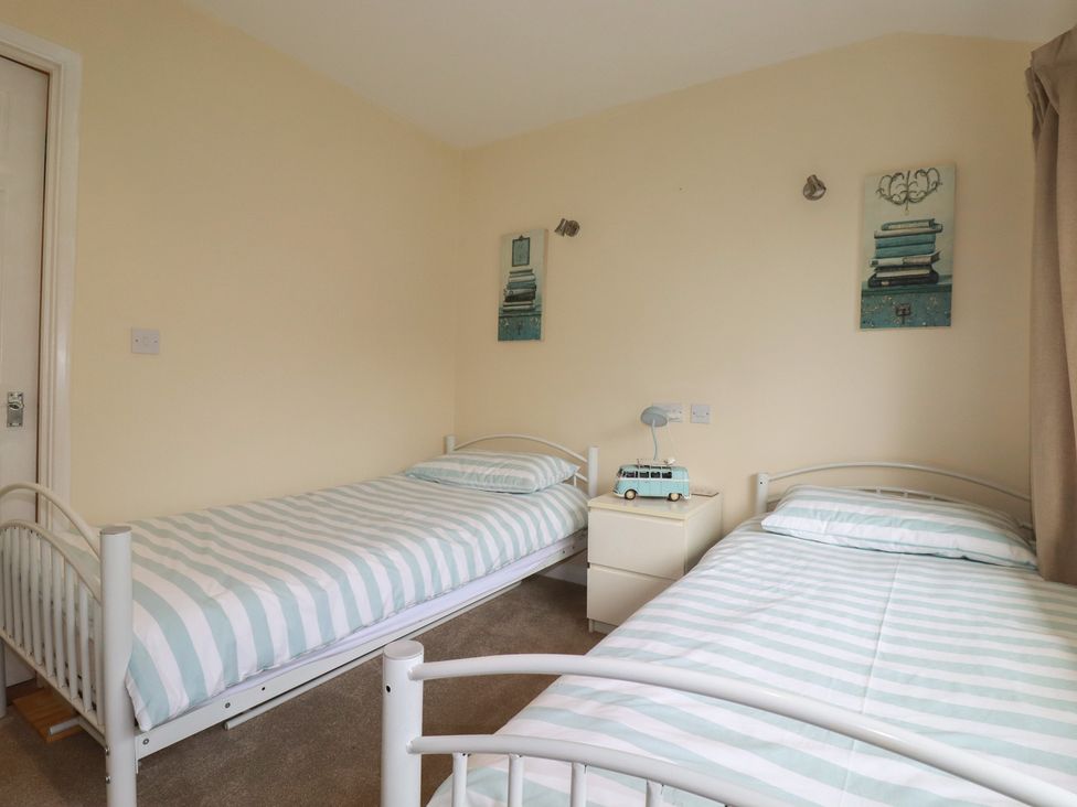A bedroom with two single beds and a nightstand at Poolside, Atlantic Reach resort, near St Columb Major