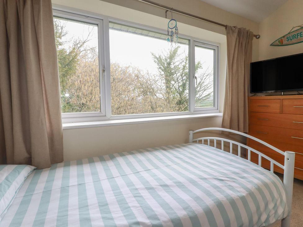 A bedroom with a bed and window at Poolside Atlantic Reach resort near St Columb Major