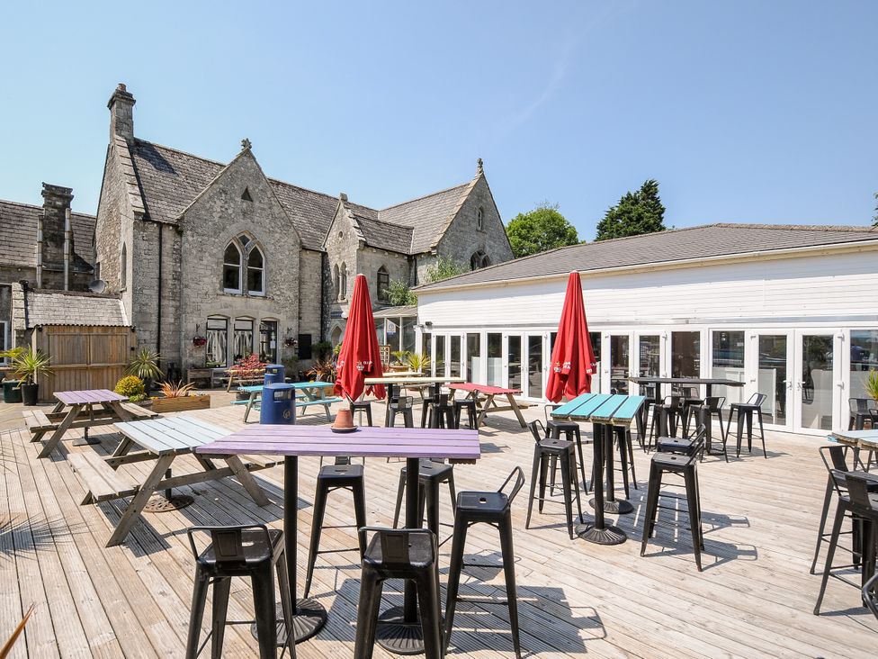An outdoor seating area with tables and umbrellas at Poolside in St Columb Major