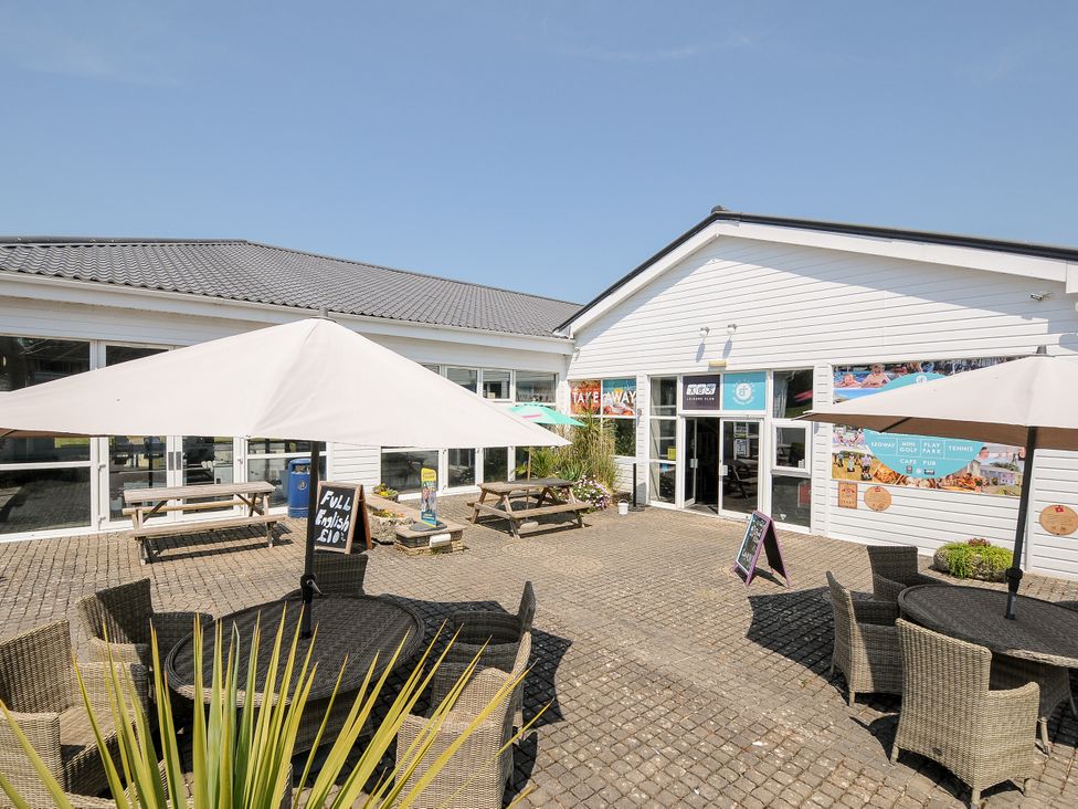 An outdoor dining area with tables and umbrellas at Poolside in St Columb Major