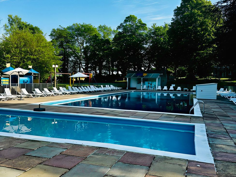 An outdoor pool area with sun loungers and a changing room at Poolside 66 Atlantic Reach, Atlantic Reach Resort, Newquay, Cornwall