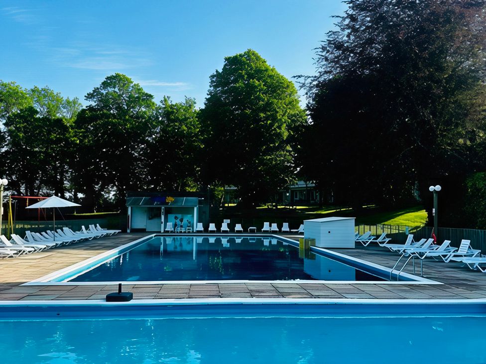 An outdoor pool area with loungers and a kiosk at Poolside 66 Atlantic Reach Resort, Newquay, Cornwall