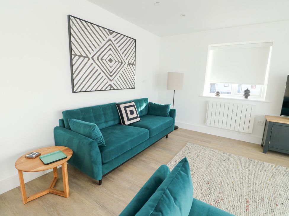A living room with a teal sofa and coffee table at Glynllifon 4 in Marianglas