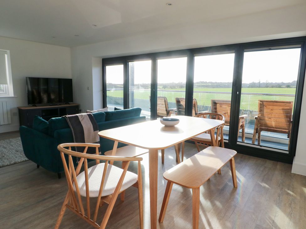 A living room with a sofa and dining table at Glynllifon 4 in Marianglas