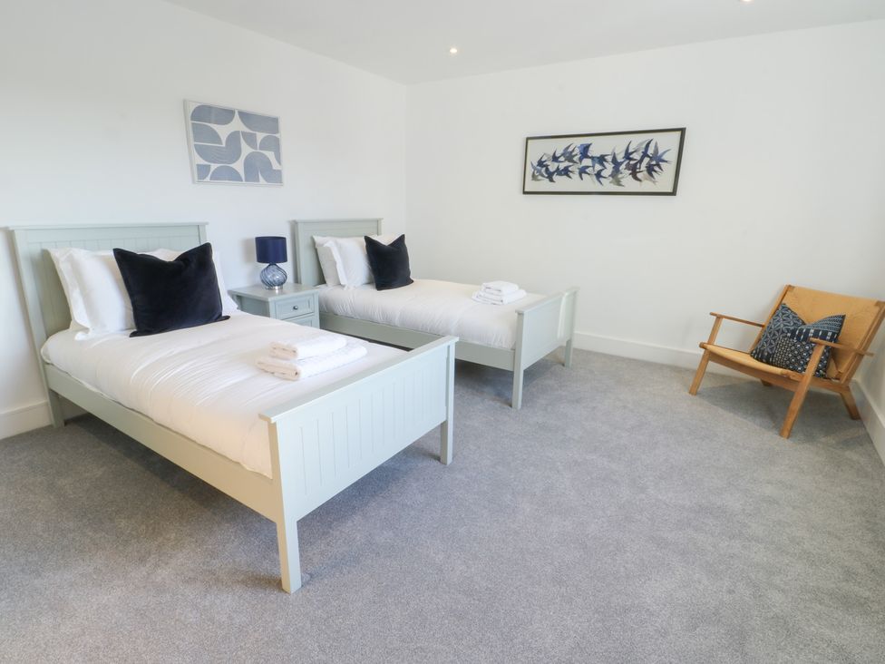 A bedroom with two single beds and a chair at Glynllifon 4 in Marianglas