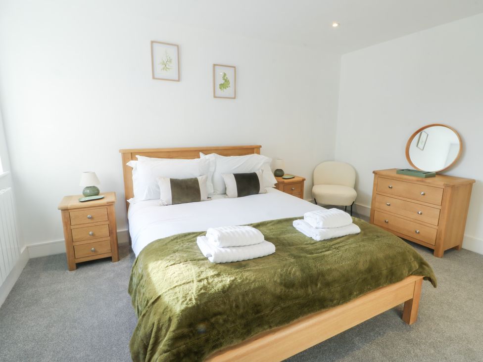 A bedroom with a bed and dresser at Glynllifon 4 in Marianglas