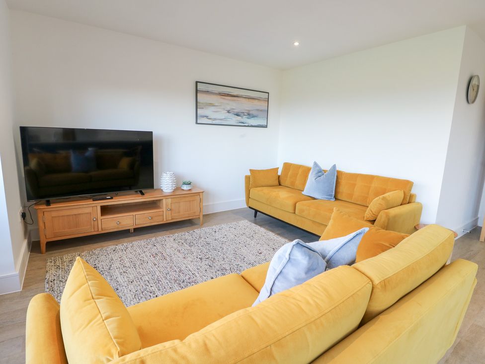A living room with a television and sofas at Glynllifon 6 in Marianglas