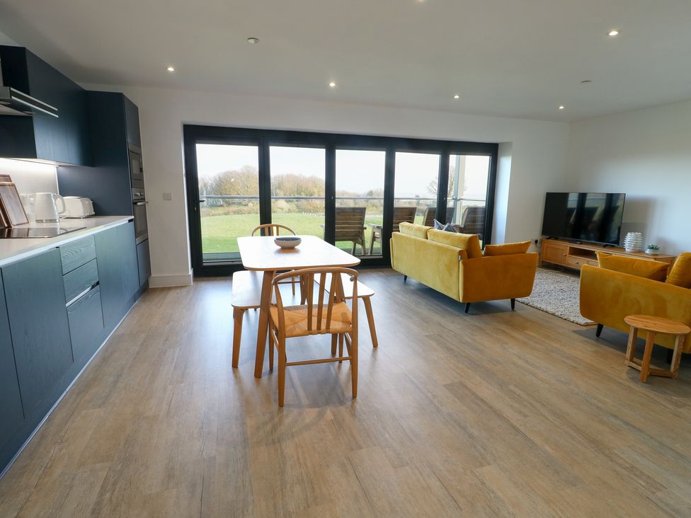 A living room with a kitchen and dining area at Glynllifon 6 in Marianglas
