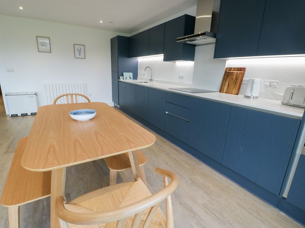 A kitchen with a table and chairs at Glynllifon 6 in Marianglas