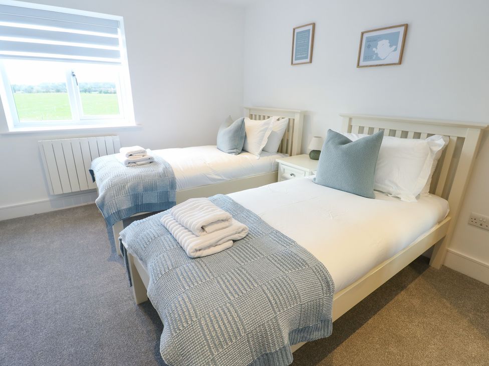 A bedroom with two single beds and a window at Glynllifon 6 in Marianglas