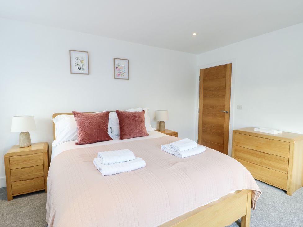 A bedroom with a bed and side tables at Glynllifon 6 in Marianglas