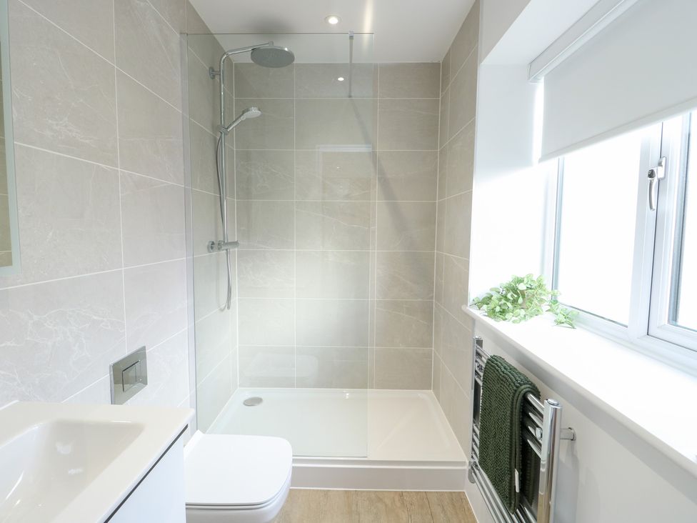 A bathroom with a shower, toilet and sink at Glynllifon 6 in Marianglas