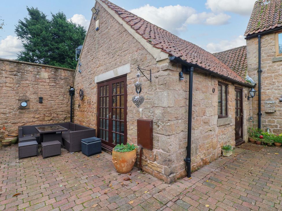 An outdoor area with stone walls and patio furniture at Magnolia Cottage in Nottingham