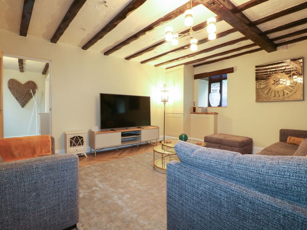 A living room with a sofa and television at Magnolia Cottage Nottingham