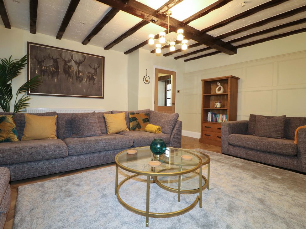 A living room with a sofa, armchairs, coffee table, and bookcase at Magnolia Cottage in Nottingham