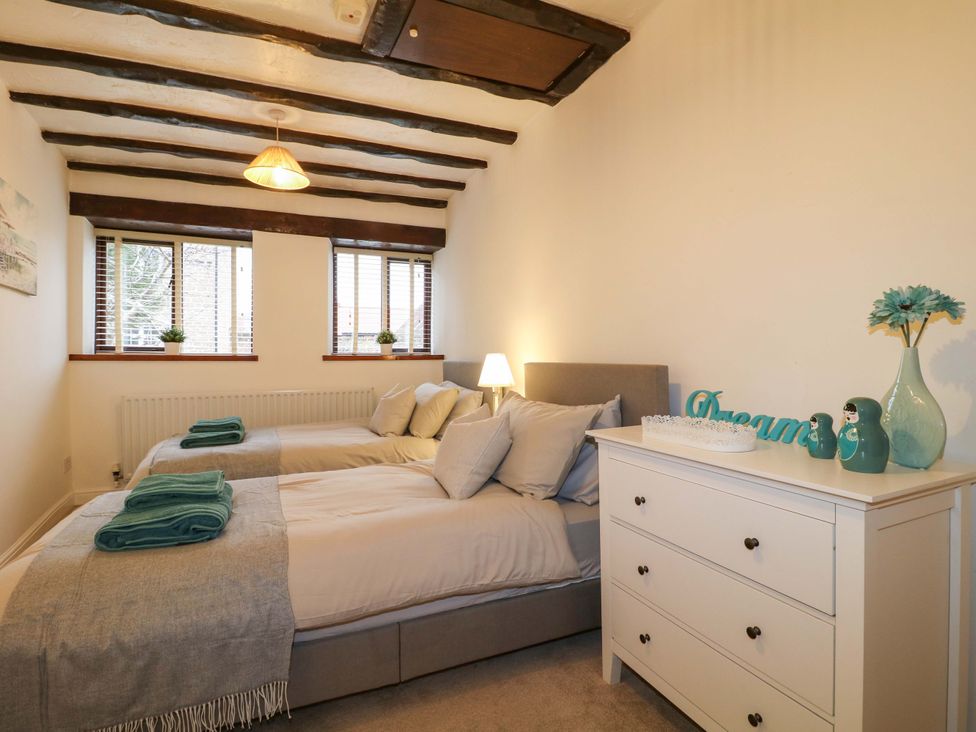 A bedroom with two beds and a white cupboard at Magnolia Cottage in Nottingham