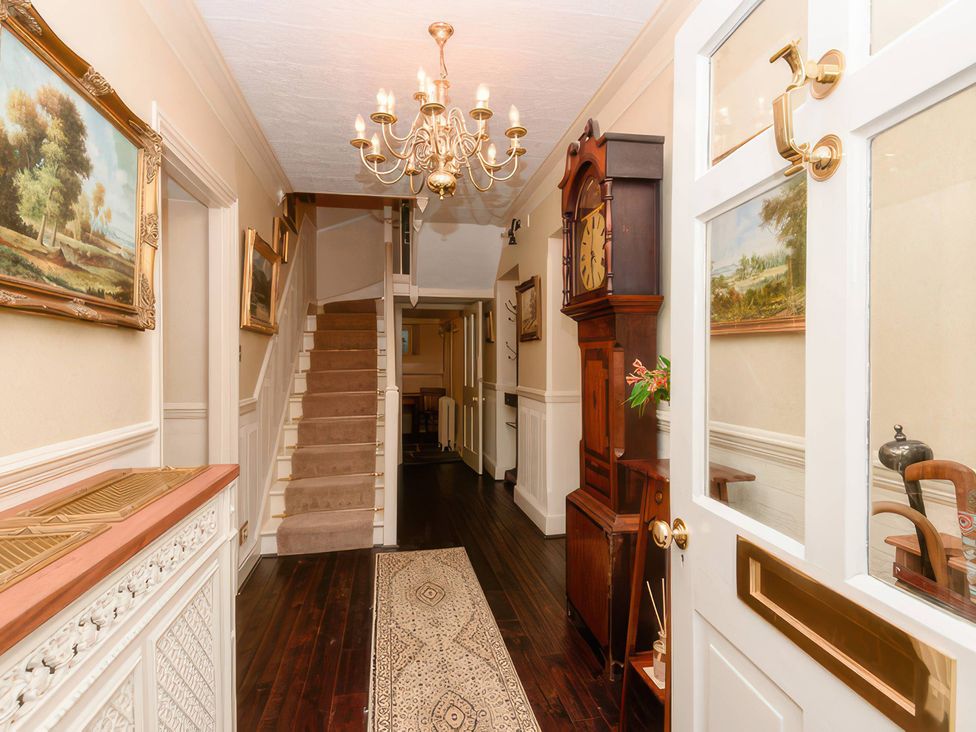 A hallway with a staircase and chandelier at Ladye Park in Liskeard