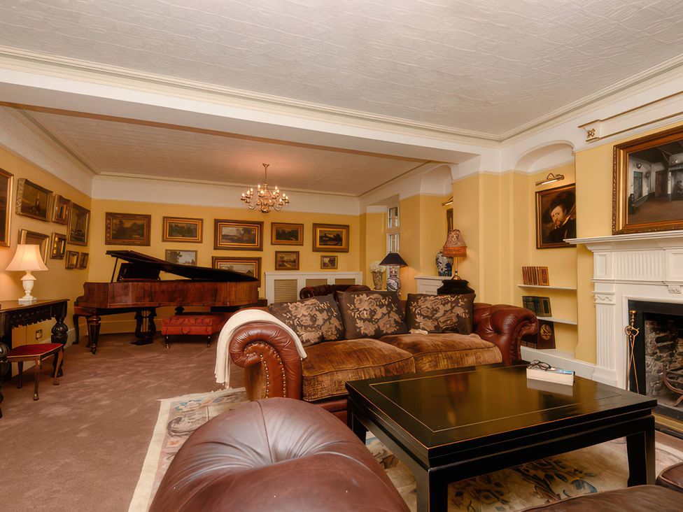 A living room with a piano and a sofa at Ladye Park in Liskeard