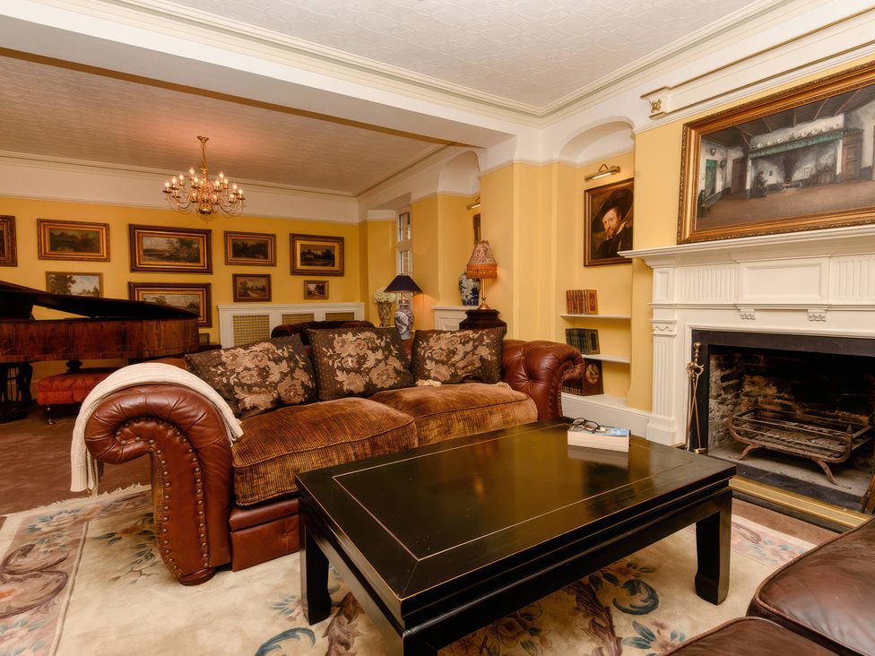 A living room with a sofa, coffee table, and piano at Ladye Park in Liskeard