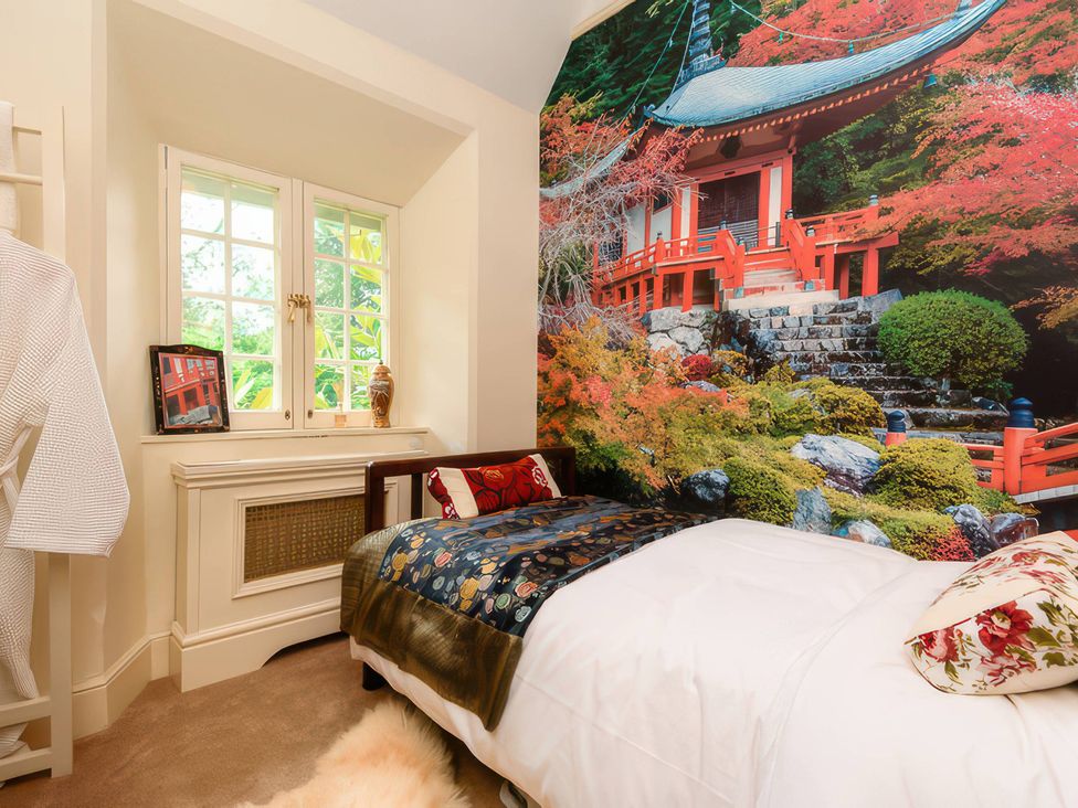 A bedroom with a bed and wall art of a temple at Ladye Park in Liskeard
