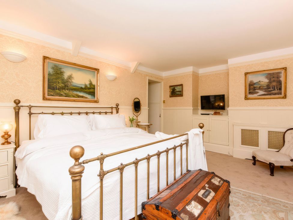 A bedroom with a bed, television, and paintings at Ladye Park in Liskeard