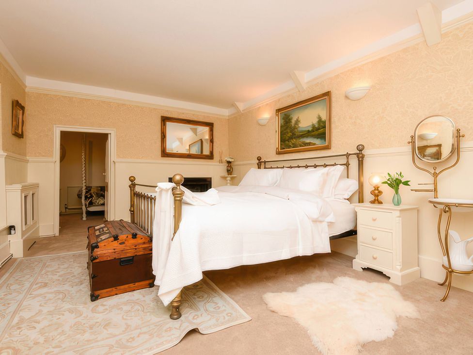 A bedroom with a bed, trunk, and paintings at Ladye Park in Liskeard