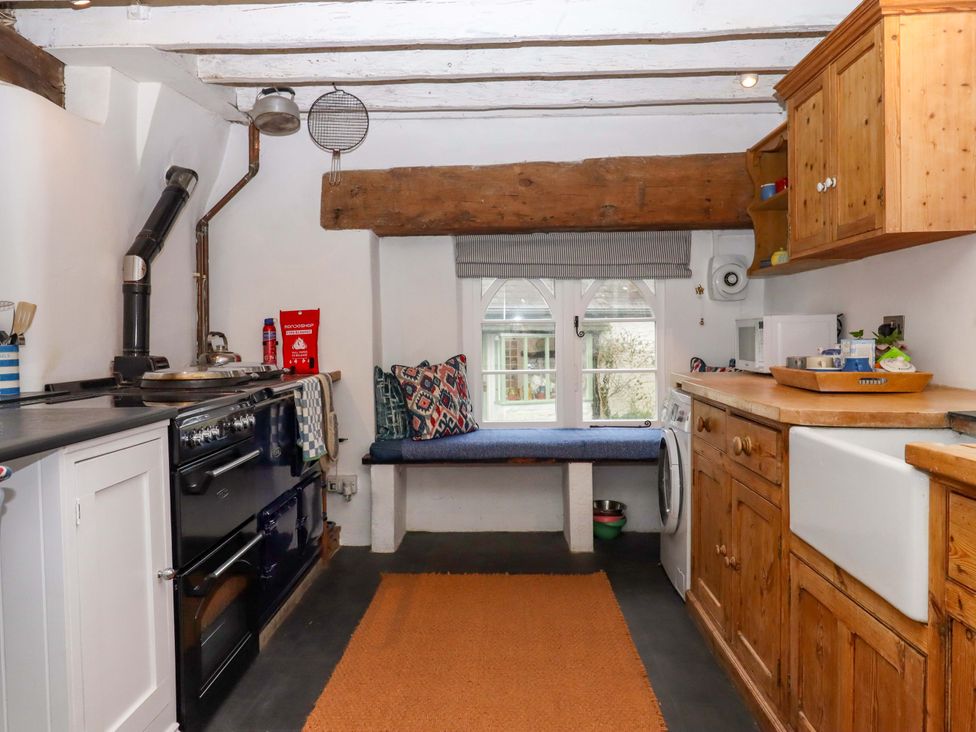 A kitchen with a stove and wooden cabinets at Old Sunday School in Welcombe near Kilkhampton