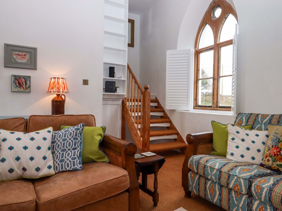 A living room with a sofa and staircase at Old Sunday School Welcombe near Kilkhampton