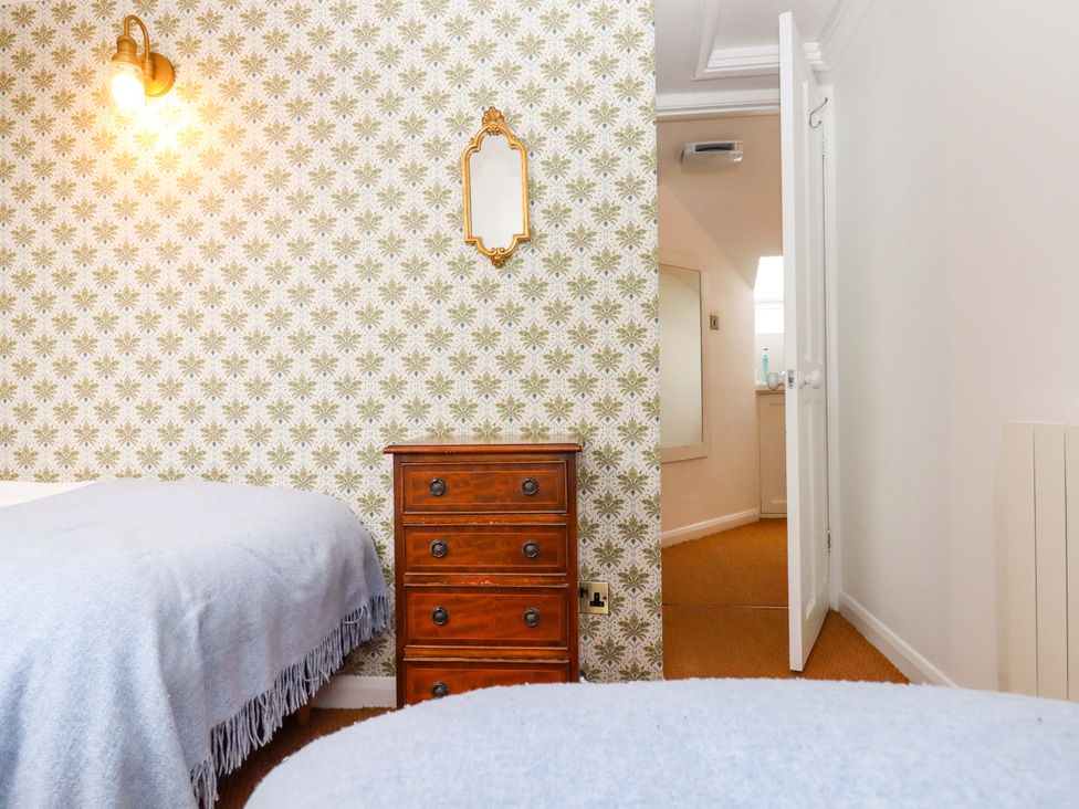 A bedroom with a dresser and two beds at Old Sunday School Welcombe near Kilkhampton