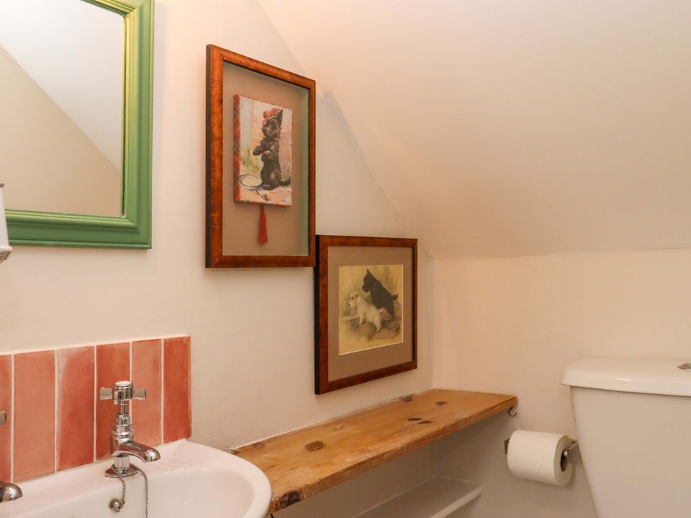 A bathroom with a sink, toilet, and wall art at Old Sunday School in Welcombe near Kilkhampton