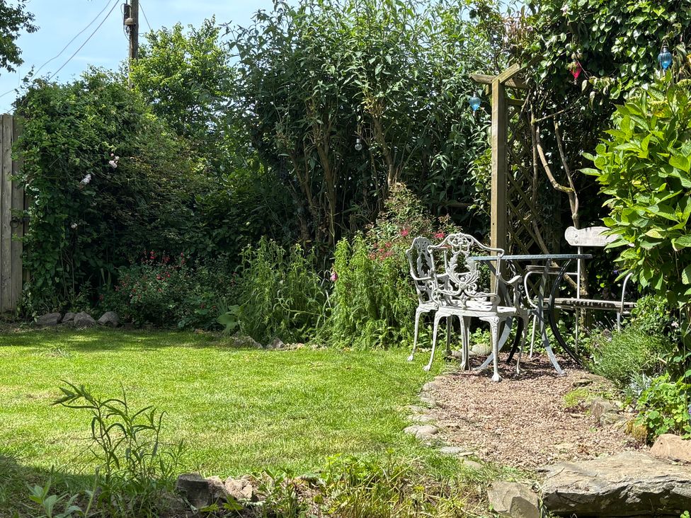A garden with grass, a bench, table, and flowers at Old Sunday School in Welcombe