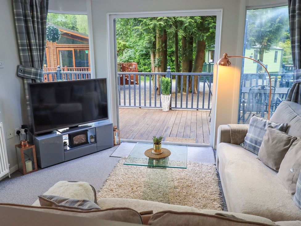 A living room with a television and a glass table at Evermore Lodge 48 Calgarth Park, White Cross Bay, Windermere