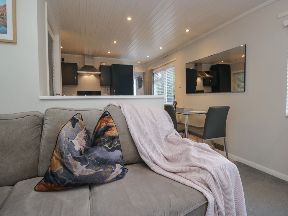 A living room with a sofa and dining area at Evermore Lodge, 48 Calgarth Park, White Cross Bay, Windermere