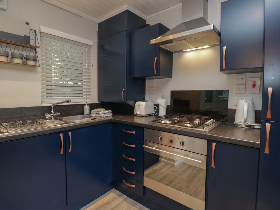 A kitchen with cabinets, sink, stove, and appliances at Evermore Lodge, 48 Calgarth Park, White Cross Bay, Windermere
