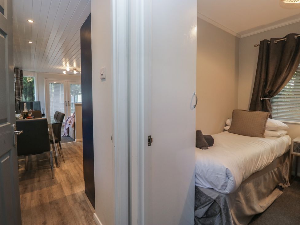 A bedroom with a bed and a door at Evermore Lodge 48 Calgarth Park, White Cross Bay, Windermere