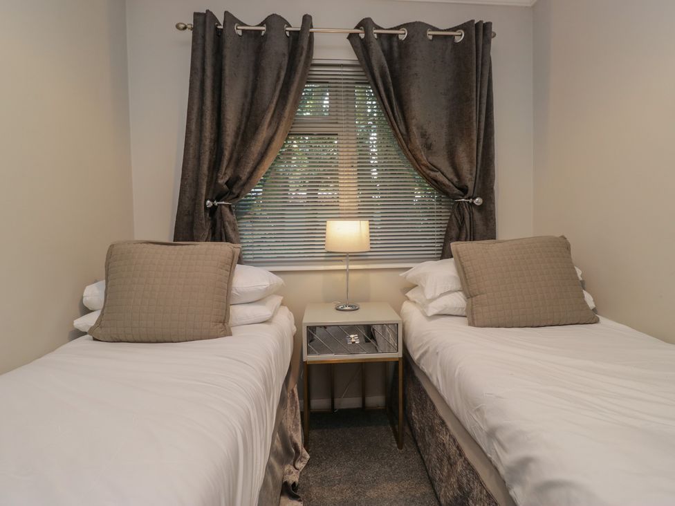 A bedroom with two beds and a lamp at Evermore Lodge, 48 Calgarth Park, White Cross Bay, Windermere