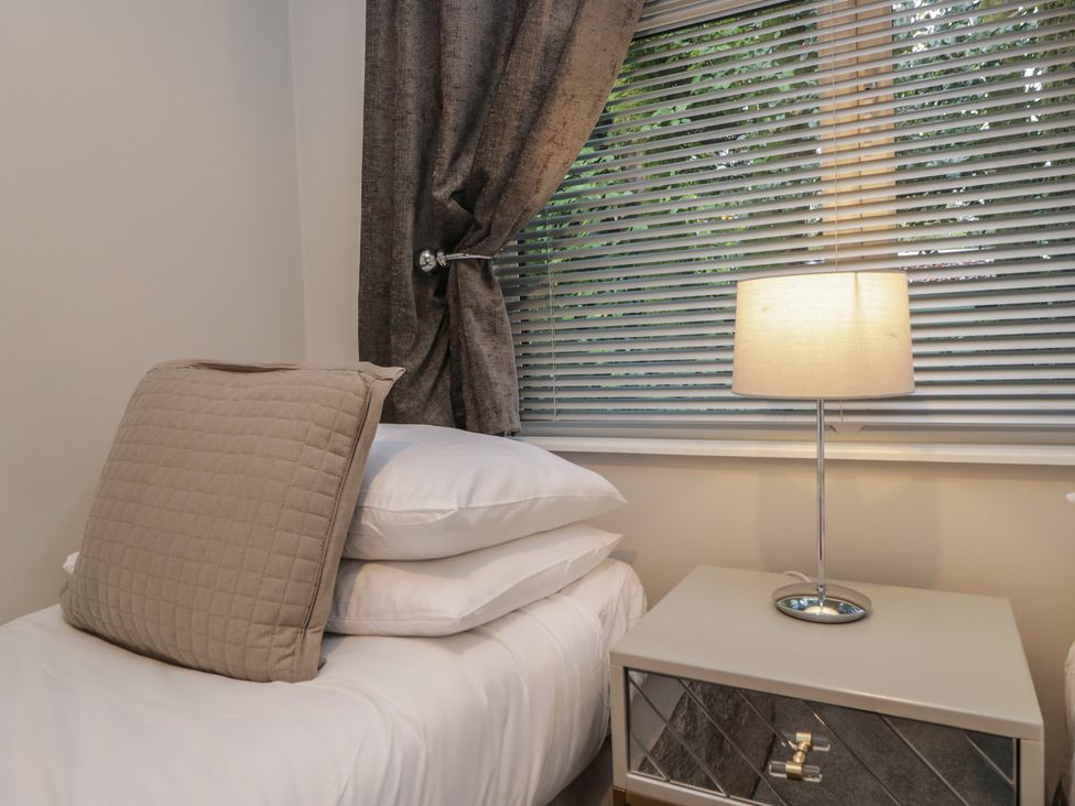 A bedroom with a bed and lamp at Evermore Lodge, 48 Calgarth Park, White Cross Bay, Windermere