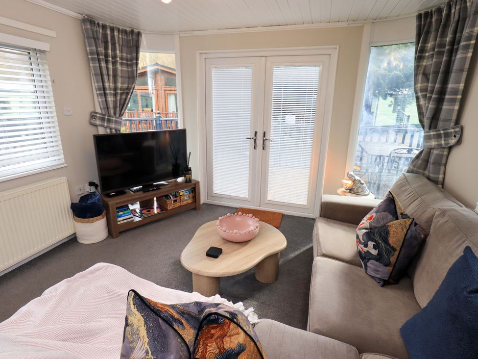 A living room with a television and a coffee table at Evermore Lodge, 48 Calgarth Park, White Cross Bay, Windermere