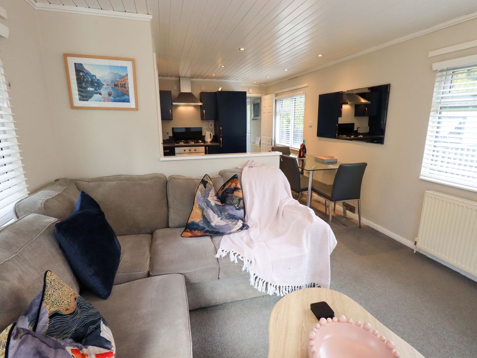 A living room with a sofa and dining area at Evermore Lodge 48 Calgarth Park, White Cross Bay, Windermere