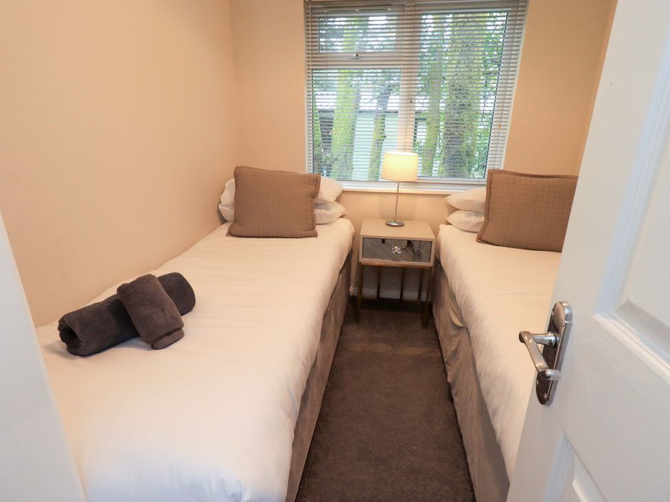 A bedroom with two single beds and a lamp at Evermore Lodge 48 Calgarth Park, White Cross Bay, Windermere