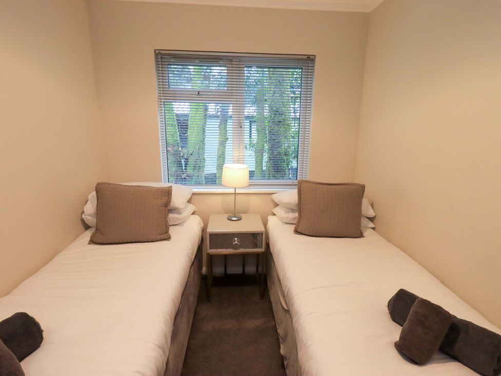 A bedroom with two beds and a lamp at Evermore Lodge, 48 Calgarth Park, White Cross Bay, Windermere