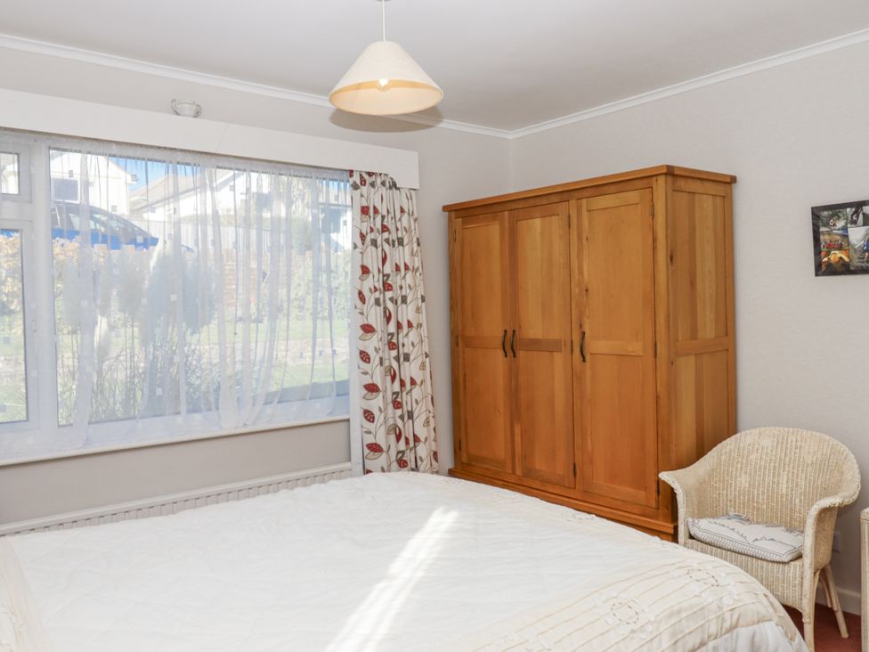 A bedroom with a bed, wardrobe, and window at Woodbury in Teignmouth