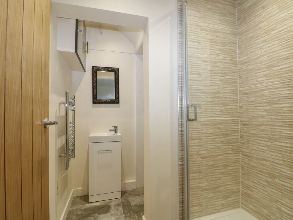 A bathroom with a sink, towel rail, and shower at Walmer Court Farmhouse in Deal